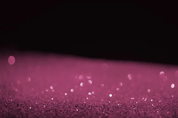 Blurred purple glowing glitter on black background — Stock Photo