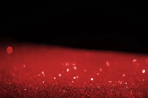 Blurred red glowing glitter on black background — Stock Photo