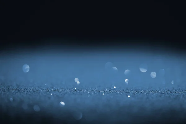 Sparking blue glitter with bokeh on black background — Stock Photo