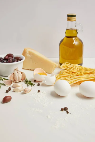 Vista de cerca de los ingredientes arreglados para cocinar pasta italiana en la mesa blanca - foto de stock