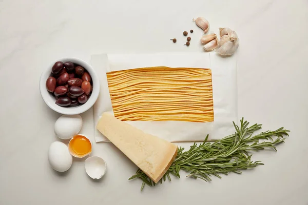 Flat lat with assorted italian pasta ingredients arranged on white marble surface — Stock Photo