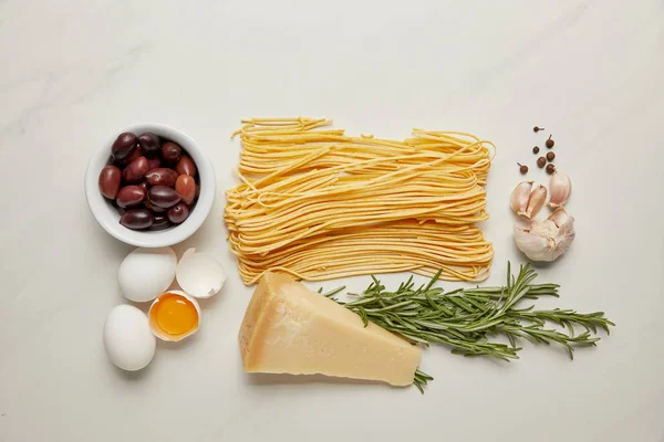 Flat lat with assorted italian pasta ingredients arranged on white marble surface — Stock Photo