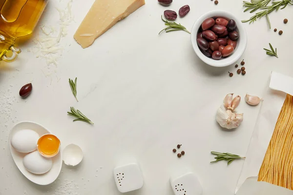 Плоский лат з інгредієнтами італійської пасти, розташованими на білій мармуровій поверхні — стокове фото