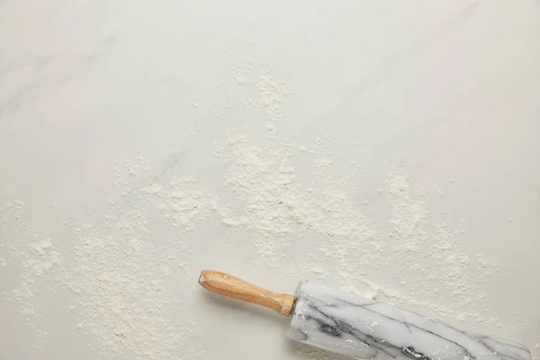 Top view of rolling pin and flour on white marble tabletop — Stock Photo