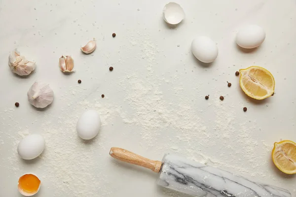 Pose plate avec rouleau à pâtisserie et ingrédients pour pâtes italiennes disposées sur plateau en marbre blanc — Photo de stock