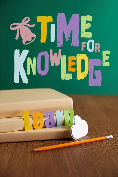 Books, pencil, cloud sign and learn lettering on wooden table with 