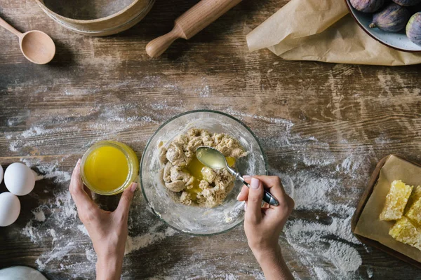 Plan recadré de la femme préparant la pâte dans un bol en verre sur une table en bois rustique — Photo de stock