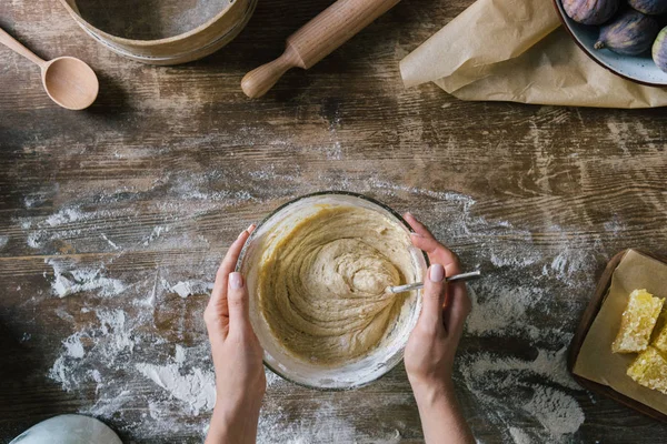 Cropped shot of woman holding bowl of dough on rustic wooden table — Stock Photo