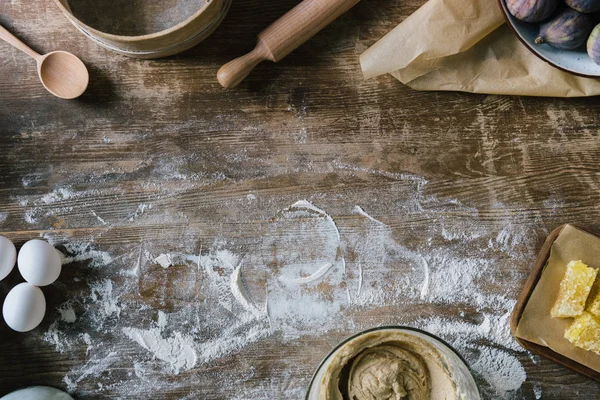 Vista superior da mesa de madeira rústica bagunçada com farinha derramada e ingredientes de cozimento — Fotografia de Stock