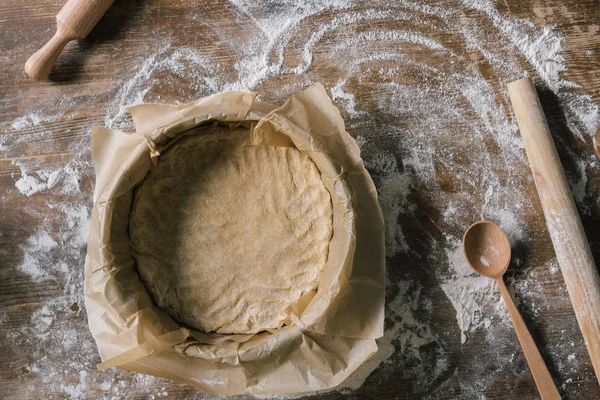 Forma di cottura con carta pergamena su tavola rustica di legno ricoperta di farina — Foto stock