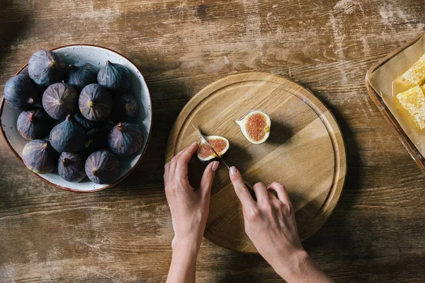 Cropped shot of woman cutting fig on rustic wooden table — Stock Photo