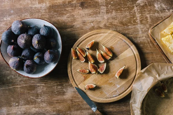 Pile de figues mûres dans un bol et sur une planche à découper sur une table en bois rustique pendant la préparation de la tarte — Photo de stock