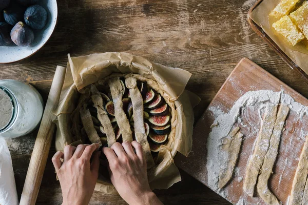 Обрезанный снимок женщины, готовящей вкусный фиговый пирог на деревенском деревянном столе — стоковое фото