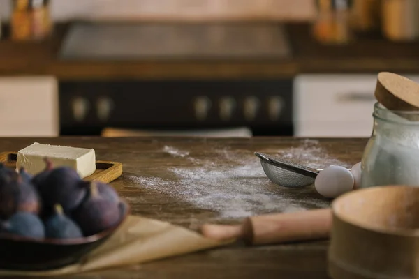 Close-up shot of fig pie ingredients standing on wooden table covered with flour — Stock Photo