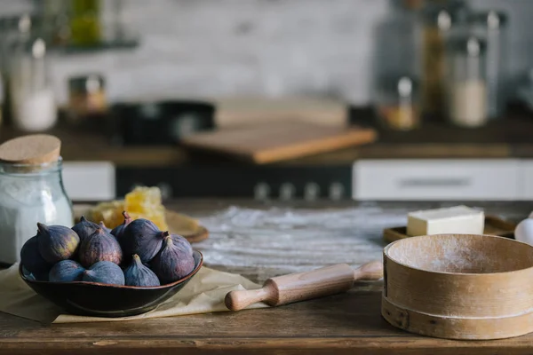 Close-up shot of fig pie ingredients standing on rustic wooden table covered with flour — Stock Photo