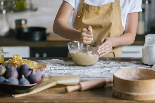 Cropped shot of woman mixing dough for pie with spoon on rustic wooden table — Stock Photo
