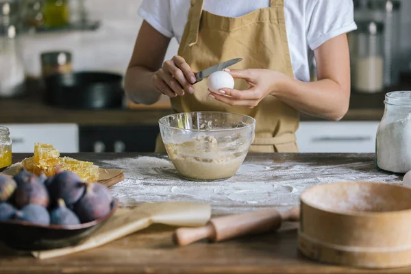 Schnittwunde an Frau in Schürze, die Ei bei Kuchenzubereitung in Schüssel bricht — Stockfoto