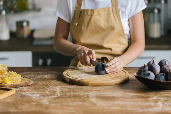 Plan recadré de femme en tablier de coupe figues sur table en bois rustique — Photo de stock