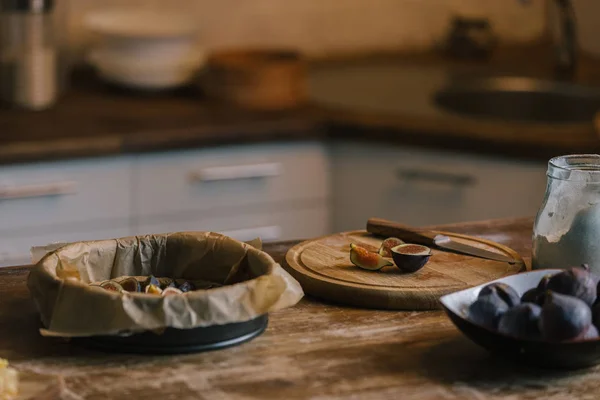 Pile de figues avec planche à découper et forme de cuisson pour tarte sur table en bois rustique — Photo de stock