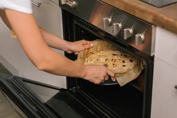 Abgeschnittene Aufnahme einer Frau, die Kuchen in den Ofen legt — Stockfoto
