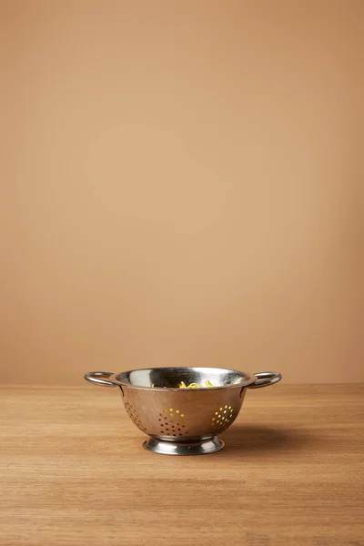 Espaguete de metal com espaguete na mesa de madeira na frente do fundo marrom claro — Fotografia de Stock