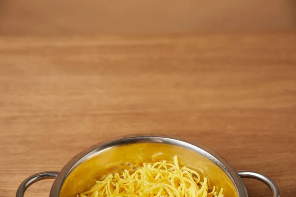 Nahaufnahme von Metallsieb mit Spaghetti auf Holztisch — Stockfoto