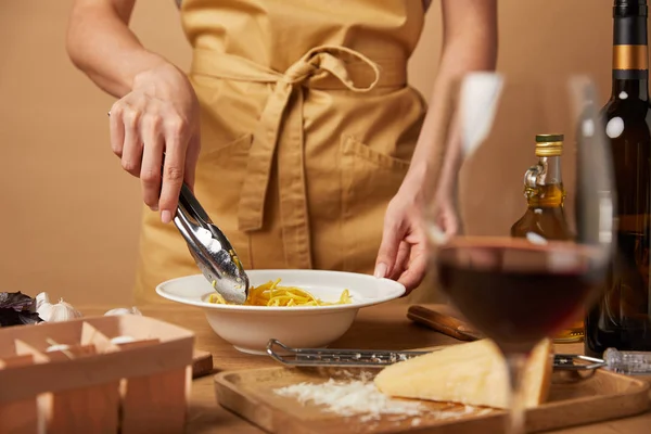 Cropped shot of woman putting spaghetti into bowl with tongs — Stock Photo