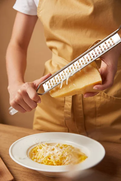 Plan recadré de fromage râpé femme sur spaghetti — Photo de stock
