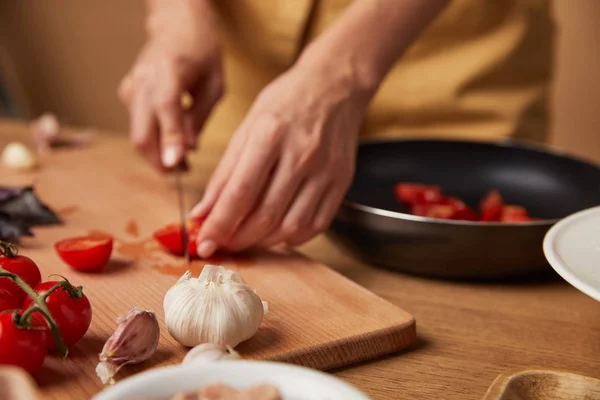 Крупным планом женщина режет помидоры черри для макарон — стоковое фото