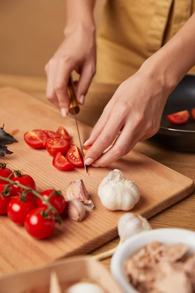 Cropped shot of woman cutting cherry tomatoes for pasta — Stock Photo