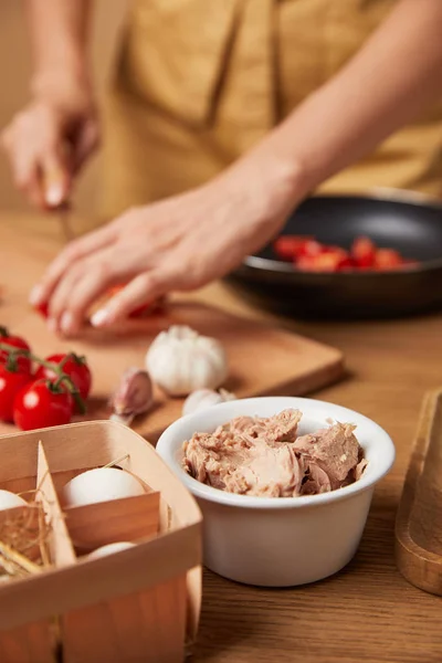 Cropped shot of woman cooking pasta with bowl of chicken meat on foreground — Stock Photo