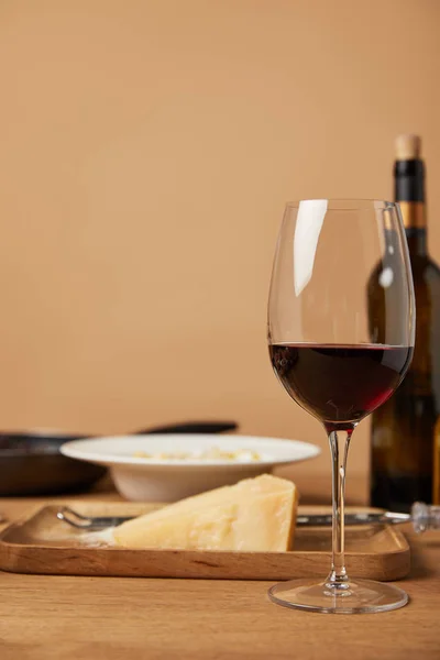 Vidro e garrafa de vinho tinto e parmesão ralado para massas na mesa de madeira — Fotografia de Stock