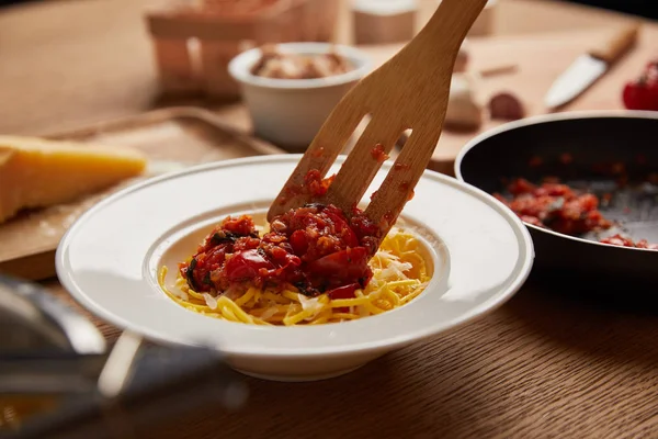 Nahaufnahme eines hölzernen Spatels, der Soße auf Pasta auf Holztisch legt — Stockfoto