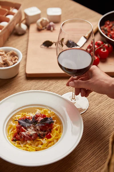 Tiro recortado de mujer con plato de pasta y copa de vino tinto — Stock Photo