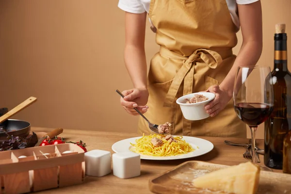 Cropped shot of woman putting chicken meat onto spaghetti in plate on wooden table — Stock Photo