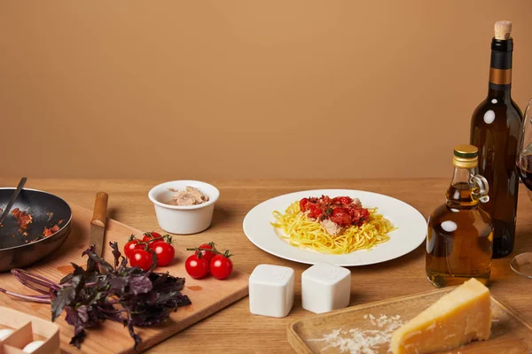 Assiette de pâtes avec divers ingrédients et vin autour sur table en bois — Photo de stock