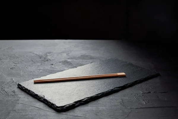 Close-up view of slate board and chopsticks on black — Stock Photo