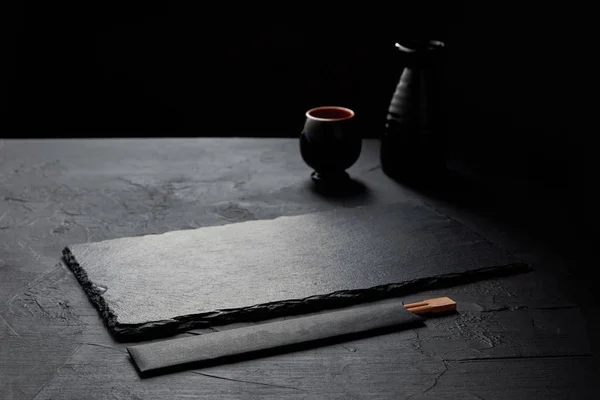 Empty black slate board, chopsticks, jug and mug — Stock Photo