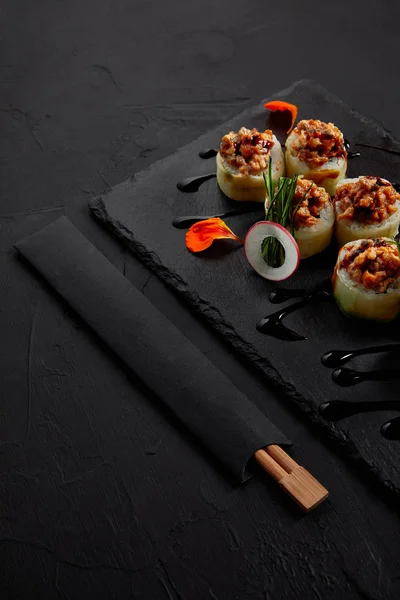 Vista close-up de delicioso rolo de sushi com enguia cremosa e maionese kimchi no tabuleiro de ardósia e pauzinhos — Fotografia de Stock