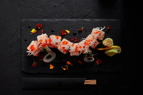 Vista superior del delicioso rollo en mamenori con camarones, salmón y aguacate en pizarra y palillos - foto de stock