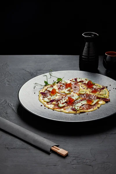 Gourmet-japanisches Gericht mit aufgeschnittenem Fisch und Avocado in Sauce auf schwarzem Teller — Stockfoto