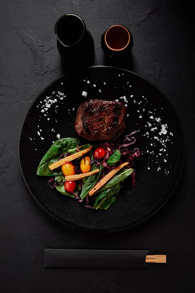 Top view of juicy beef in Teriyaki sauce with grilled cherry tomatoes, red cabbage and leaves of spinach, baby corn and kumquat — Stock Photo