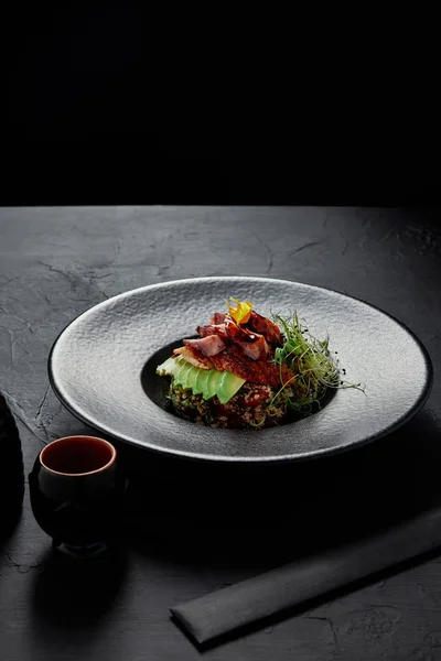 Köstliche japanische Ceviche mit Meeresfrüchten, Avocado und Kräutern auf schwarzem Teller — Stockfoto