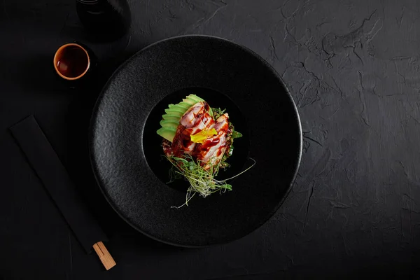 Top view of delicious traditional japanese dish with seafood, avocado and herbs on black plate — Stock Photo