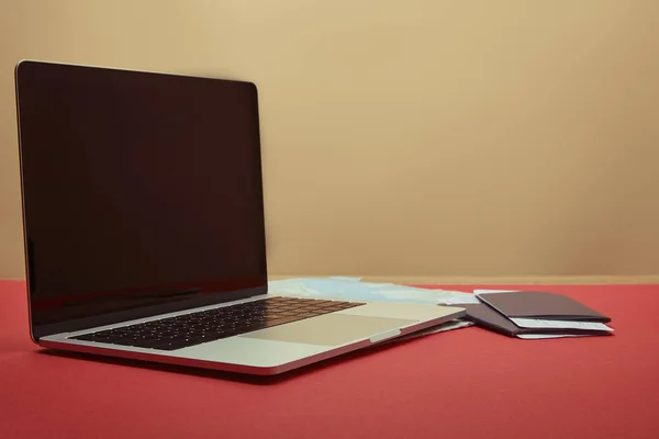 Laptop with blank screen, map, passports and tickets on red tabletop — Stock Photo