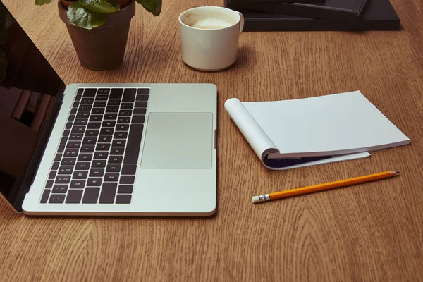 Ordinateur portable, tasse de café, cahier et crayon sur table en bois — Photo de stock