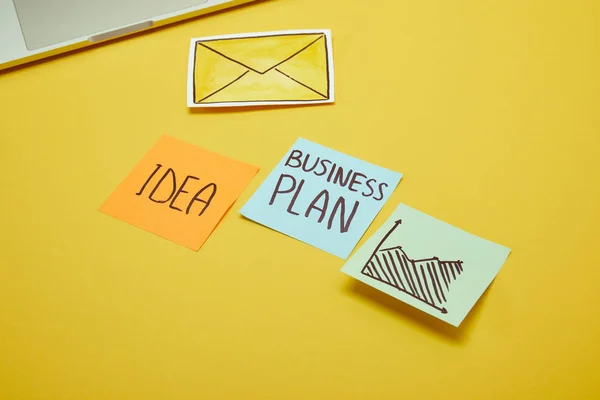 Autocollants en papier avec mots, idée et plan d'affaires sur surface jaune — Photo de stock