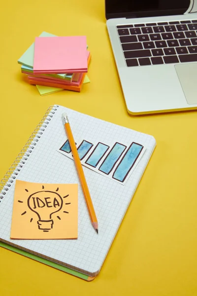 Laptop, notebook, pencil chart sign and idea sign on wooden tabletop — Stock Photo