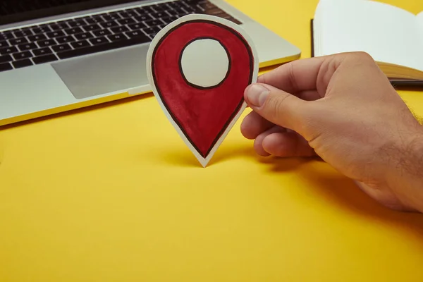 Imagem cortada do homem segurando sinal de localização de papel perto do laptop — Fotografia de Stock