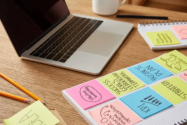 Papieraufkleber mit Geschäftsstrategie und Laptop auf Holztischplatte — Stockfoto